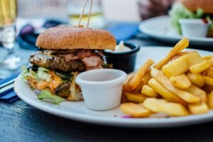 selective focus photography of burger patty, mayonnaise, and French fries served on platter