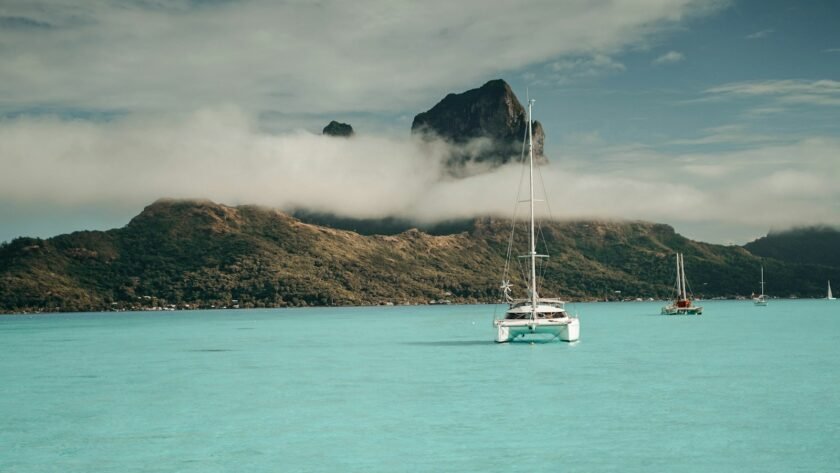 white boat on sea near mountain under white clouds during daytime