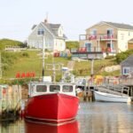 red and white boat on body of water near houses during daytime