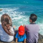 man and woman sitting on rock near body of water during daytime