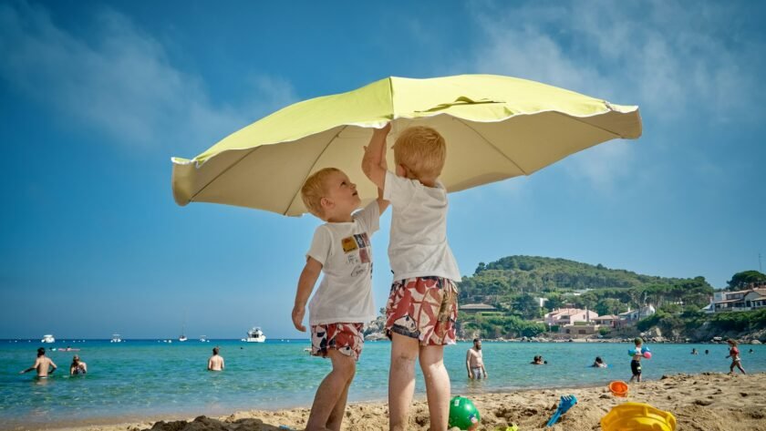 two children playing under umbrella on seashore